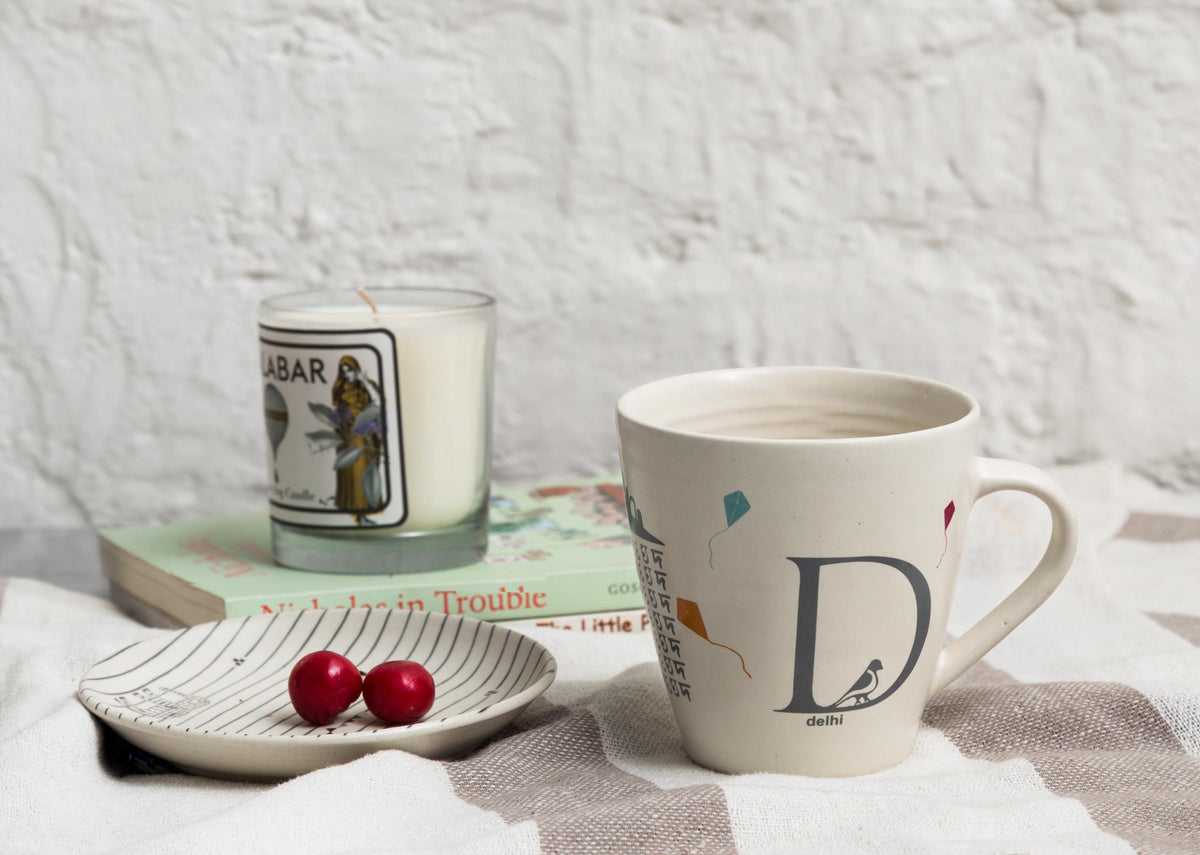 Alphabet D Mug on a striped cloth, shown in a styled setup.
