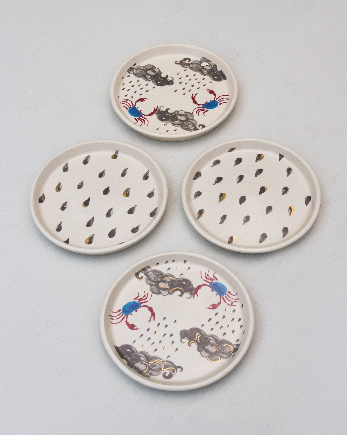 Crab Coaster Set laid out, two with raindrops and two with crabs and clouds.