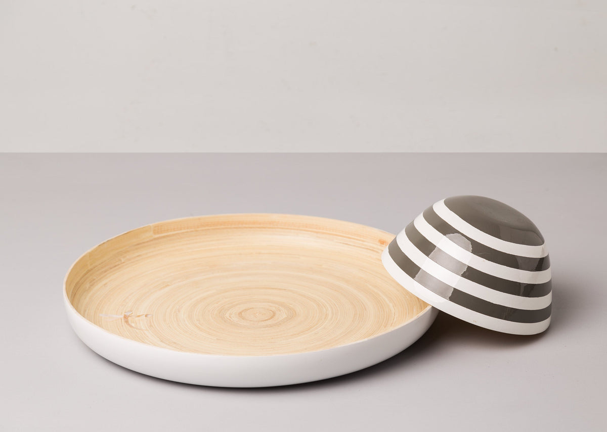 Side view of the Bamboo Chip & Dip Platter with its striped bowl tipped beside it.