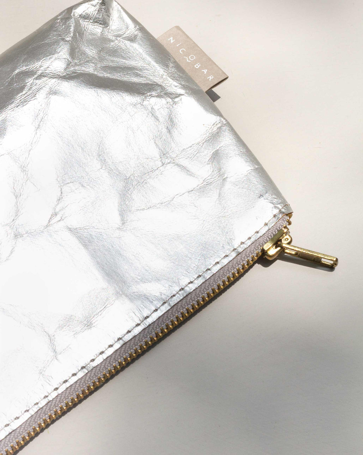 Close-up of the Silver Paper Pouch (Small) showing its gold zip and tag.