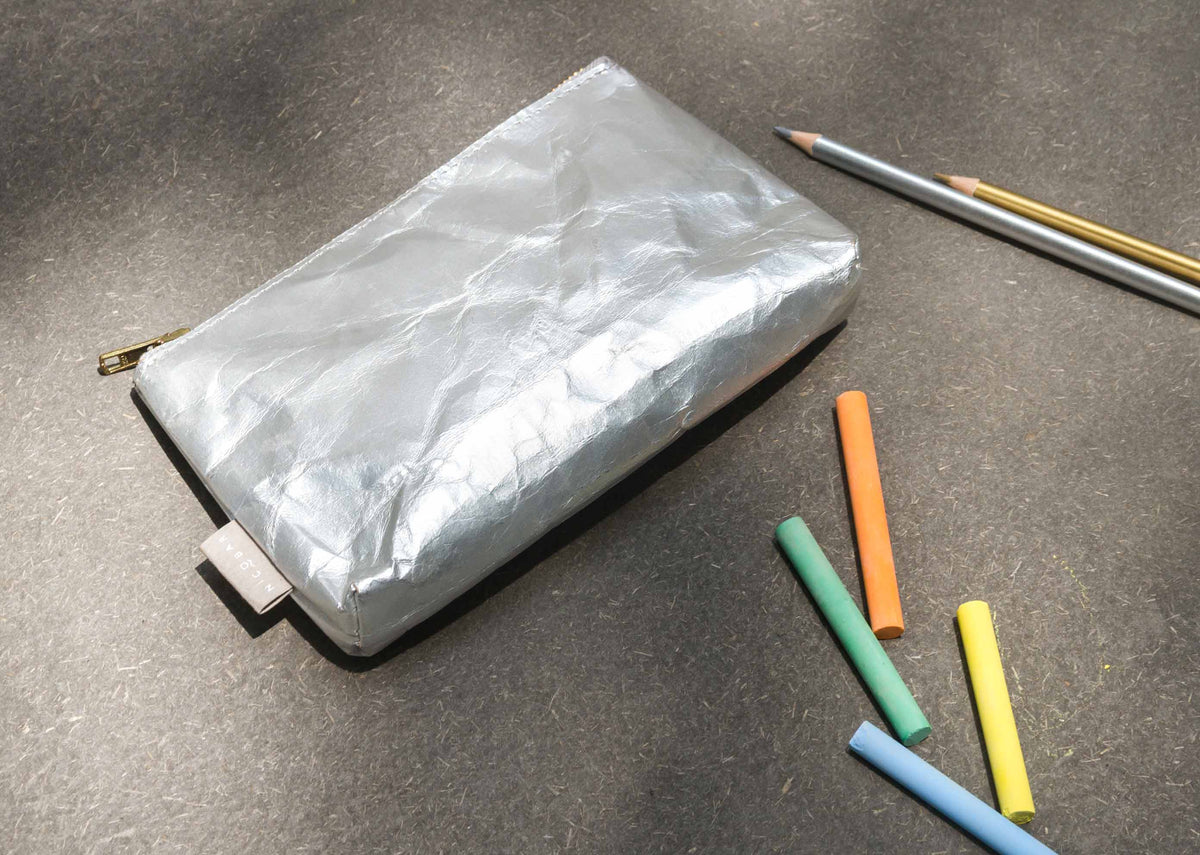 Silver Paper Pouch (Small) resting at an angle on a dark surface.