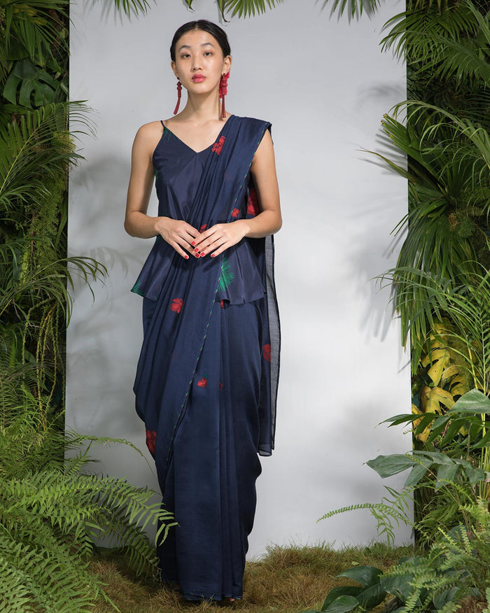 Person wearing a navy Enchanted Sari with red flower and green leaf prints.