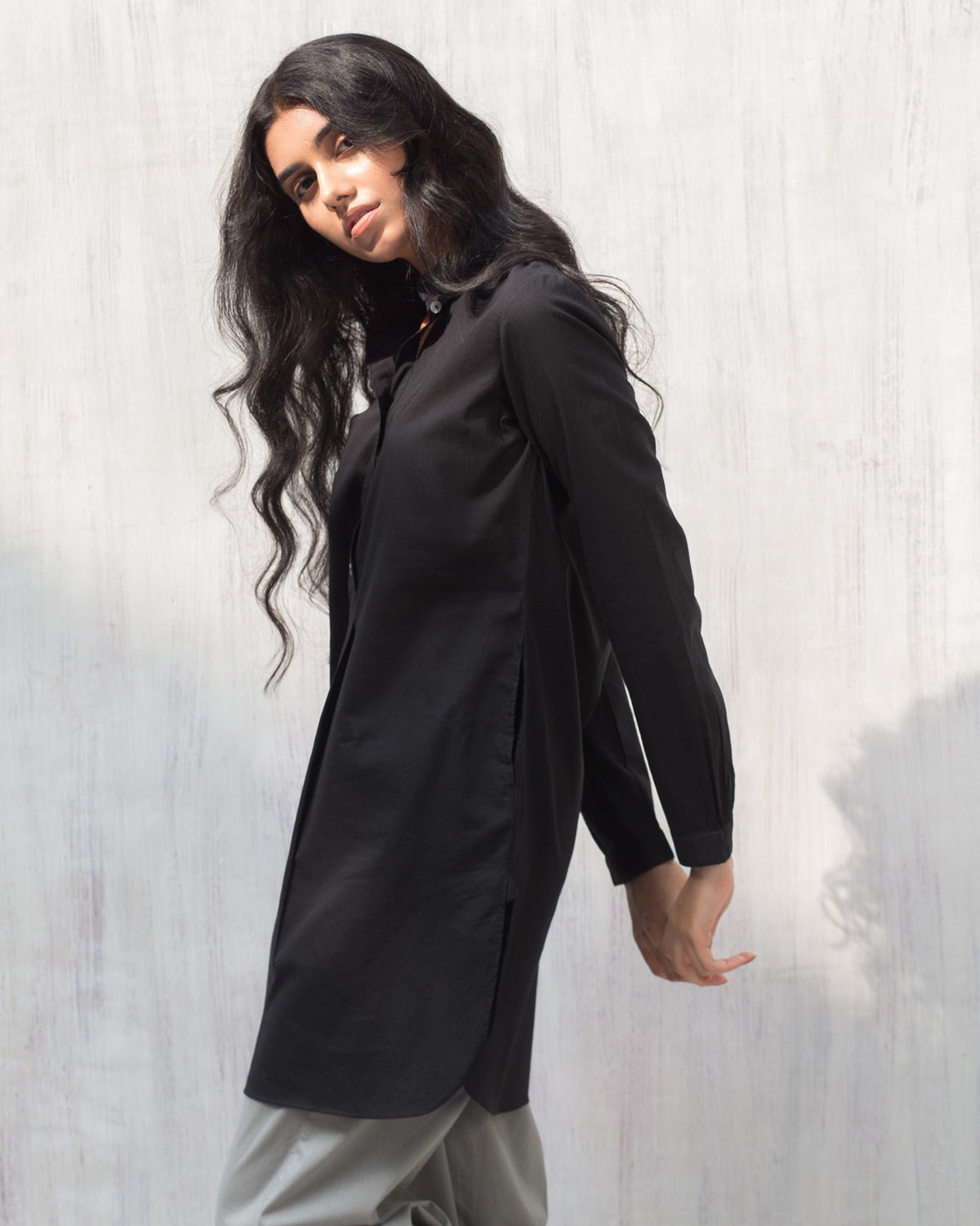 Person wearing a black Basic Mid Length Kurta, turned at an angle.