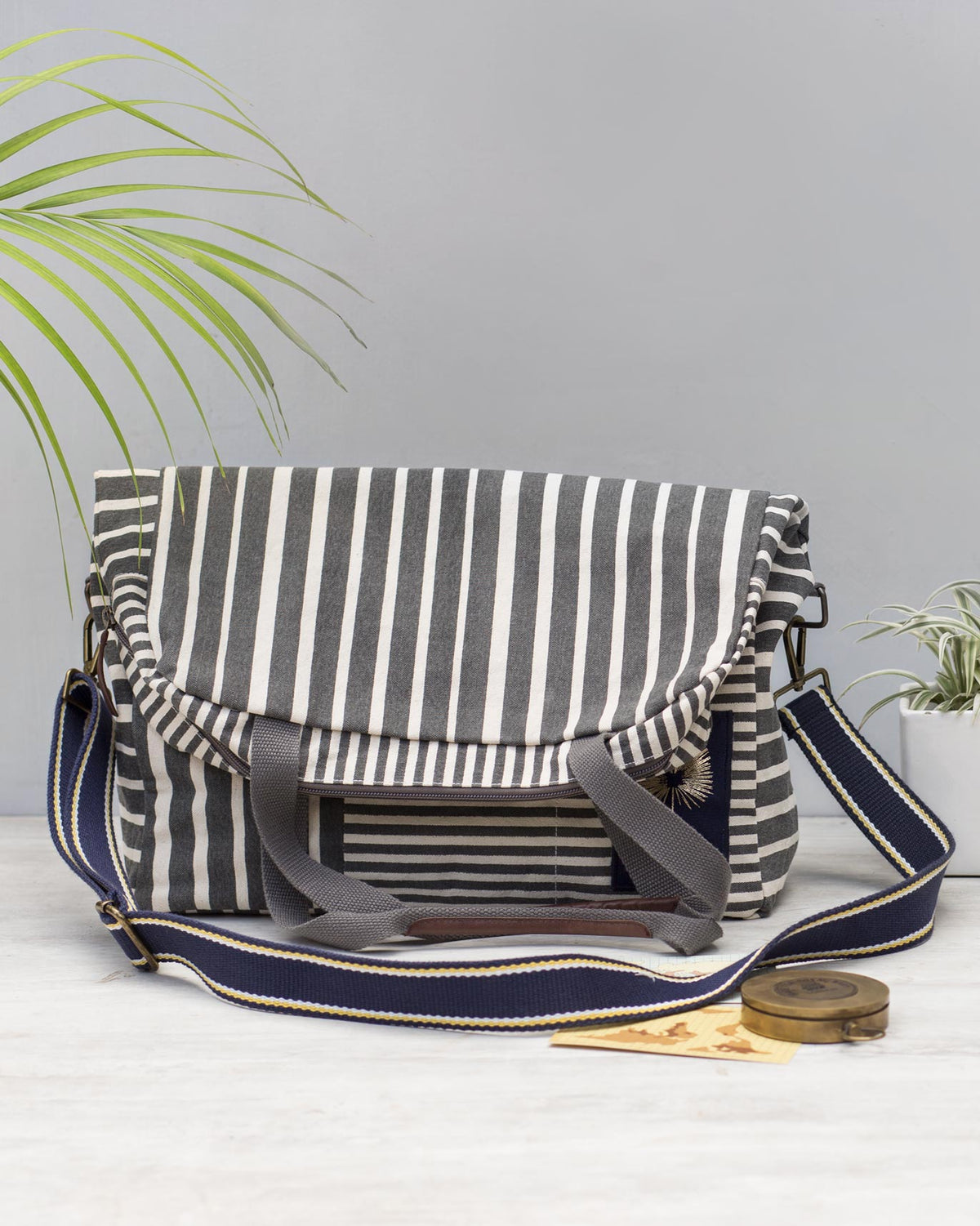 Noto Artist's bag with a striped flap and navy crossbody strap.
