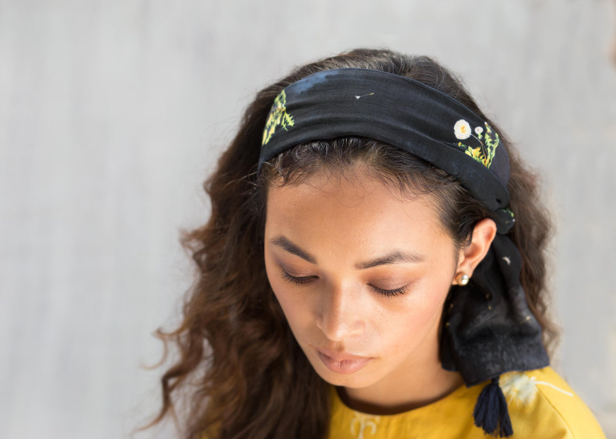 Person wearing a navy Dandelion Scarf tied as a headband.