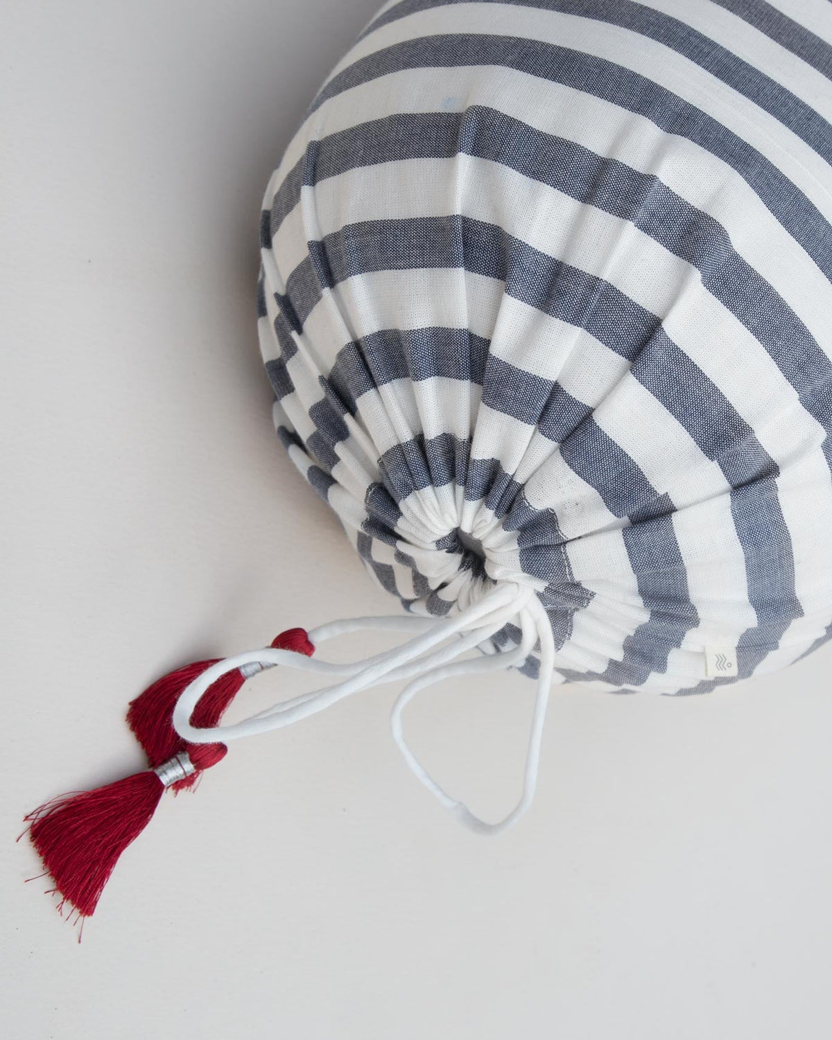 Close-up of the Ahasa Bolster Cover showing its gathered end and red tassel.
