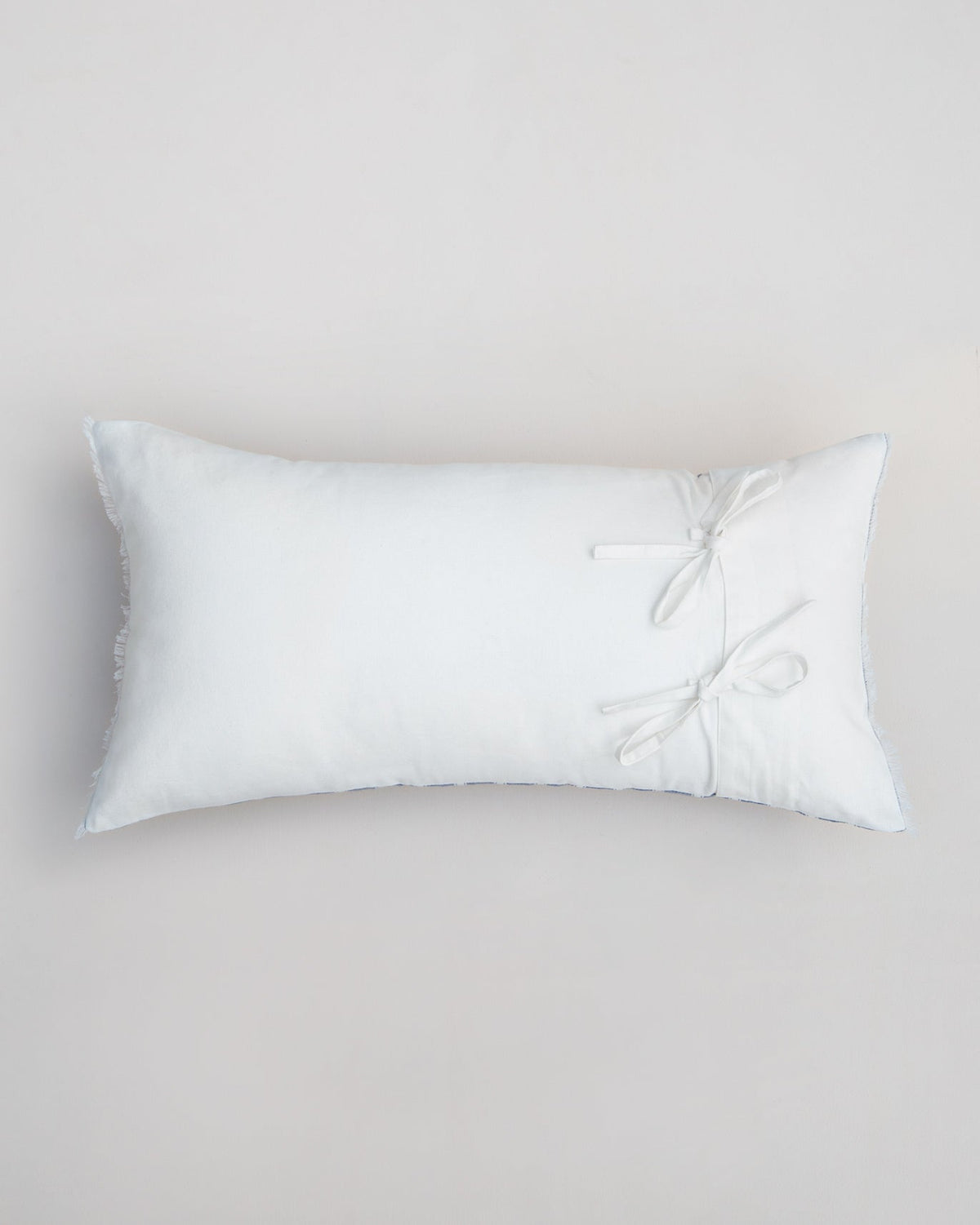 Back of Ahasa lumbar cushion cover in white, with tie bows on one side.