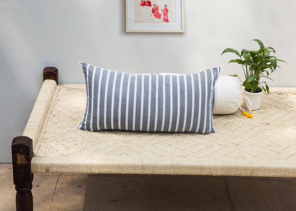 Ahasa lumbar cushion cover with blue and white stripes, shown on a daybed.