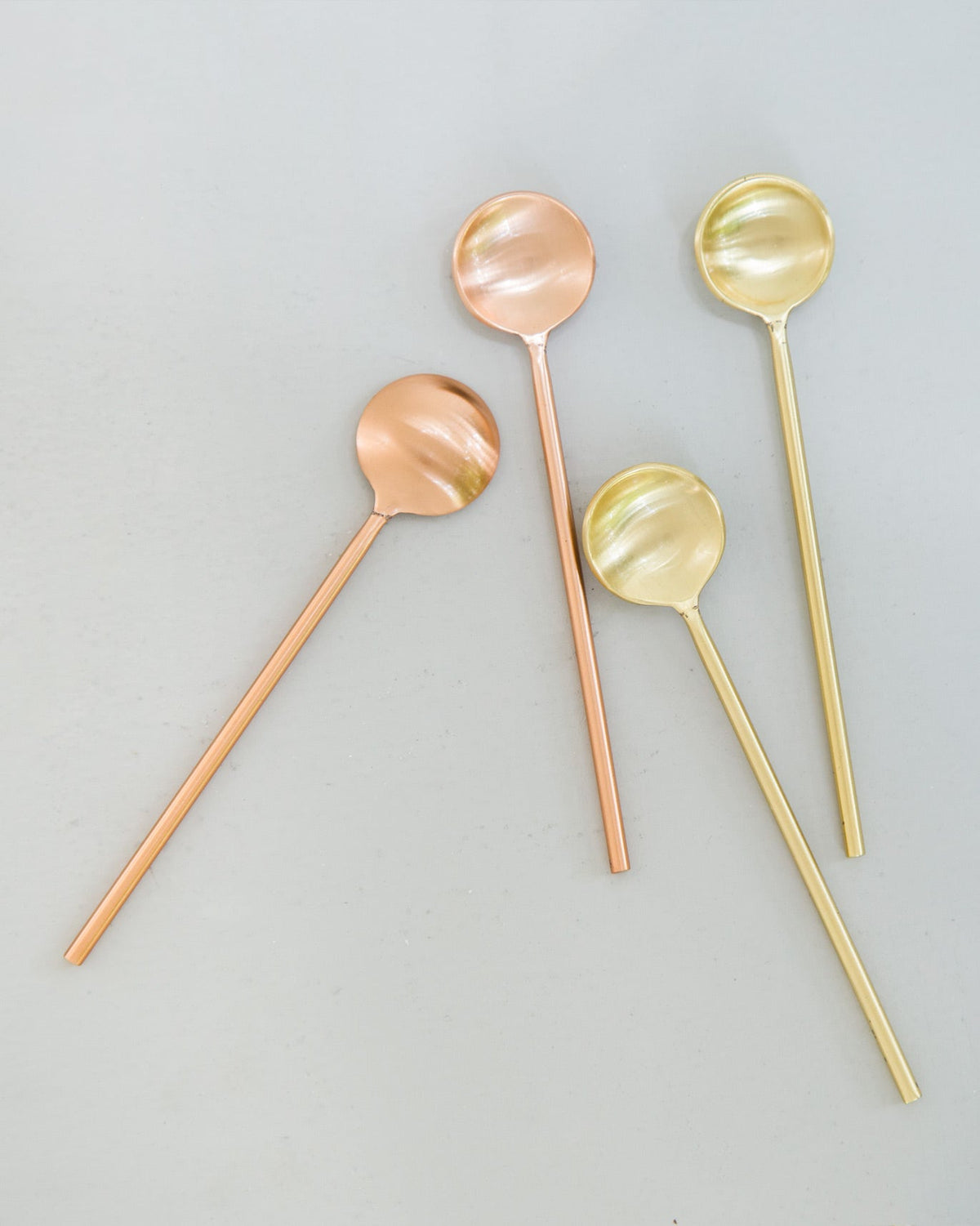 Coffee Spoons (Set of 4) scattered loosely, with gold and copper bowls.