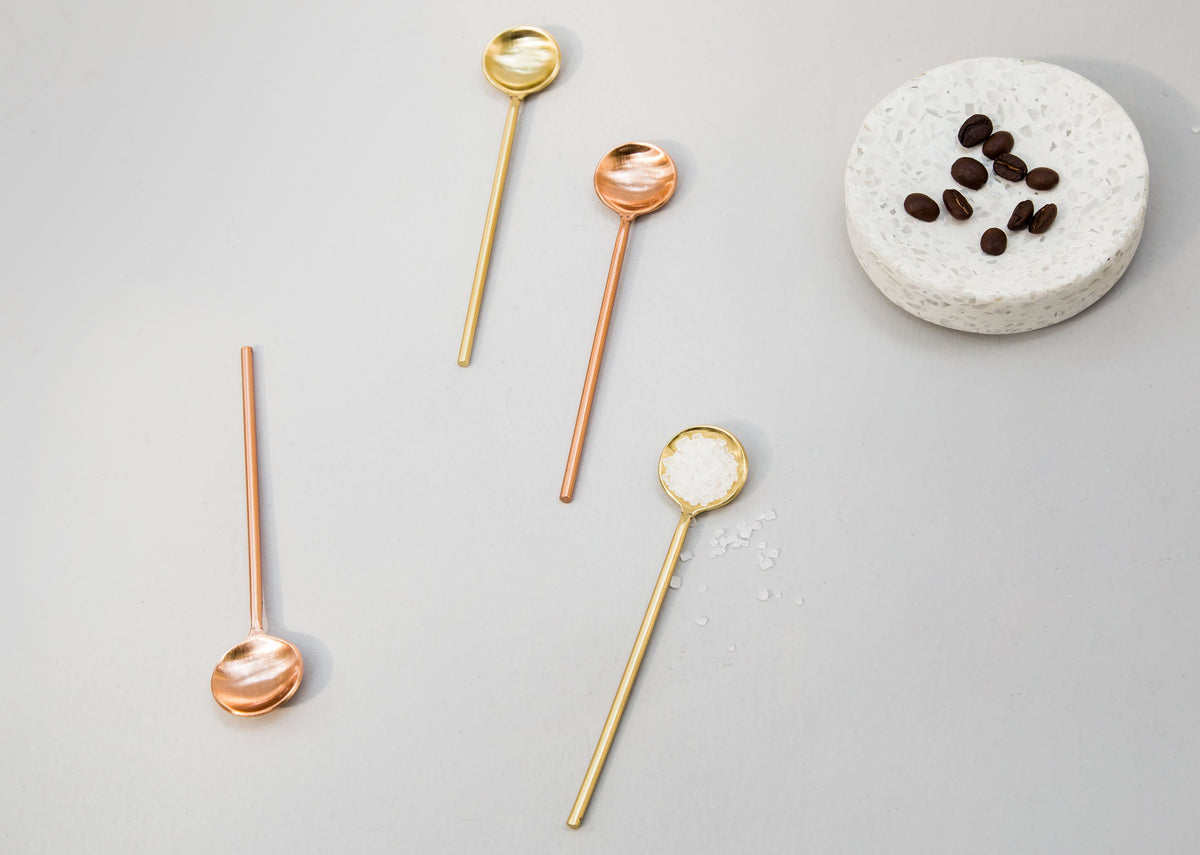 Coffee Spoons (Set of 4) with one gold spoon holding white granules, beside coffee beans.