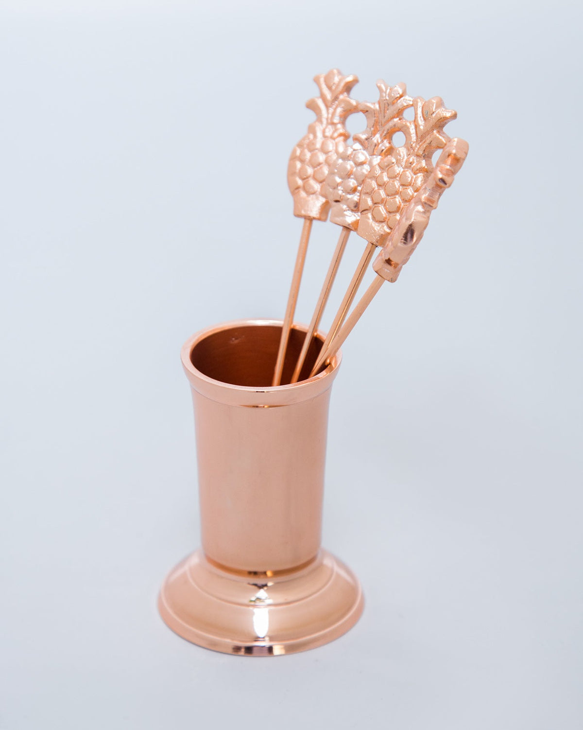 Rose gold Anasi fruit picks standing in their copper stand.