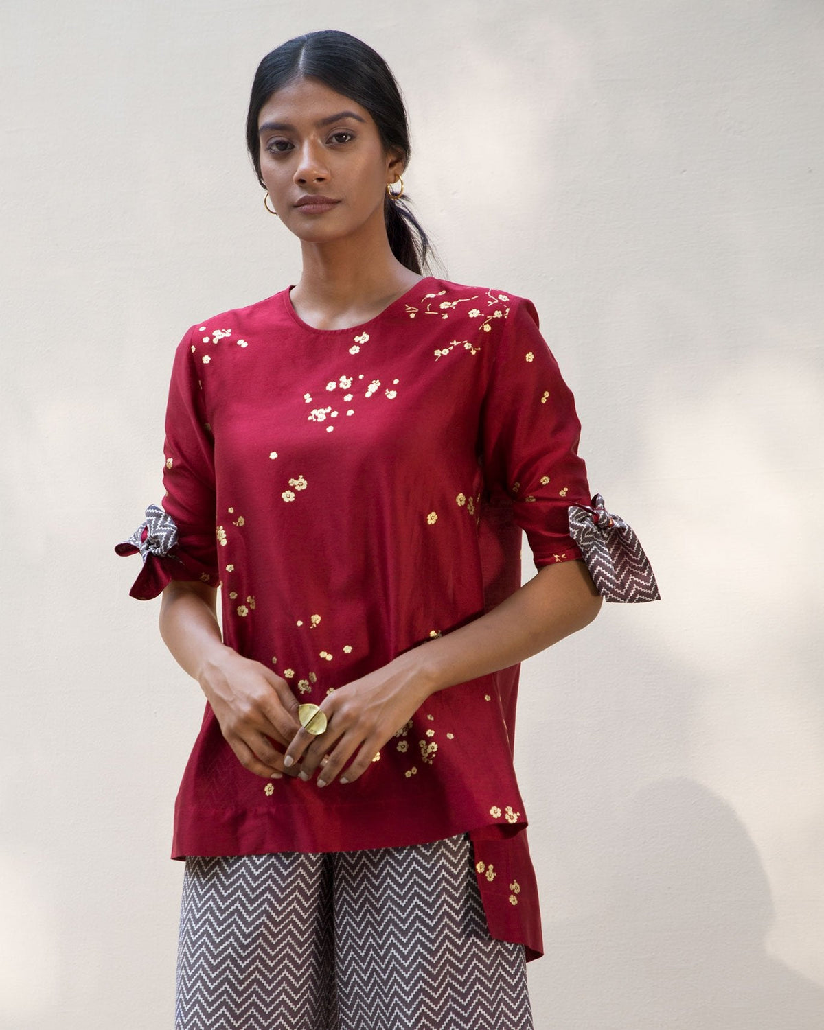 Person wearing a red Side High Slit Top with gold flecks and tie-up sleeves.