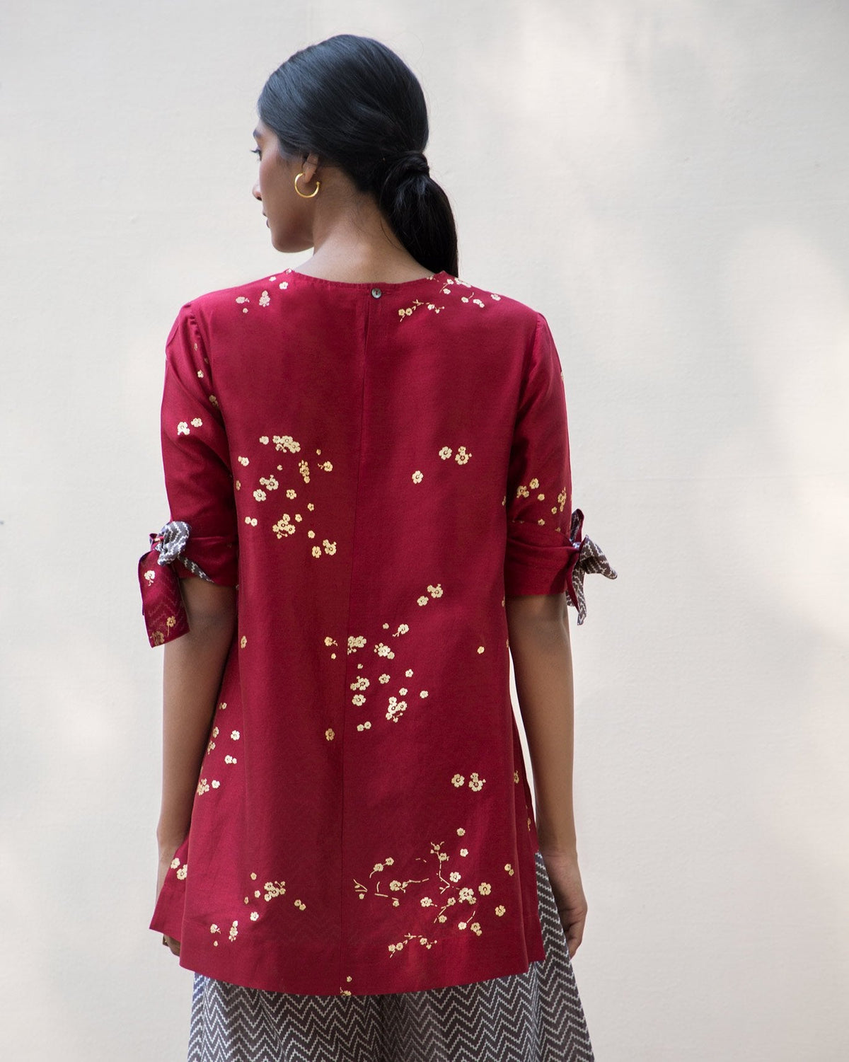 Back of a red Side High Slit Top with gold flecks worn by a person.