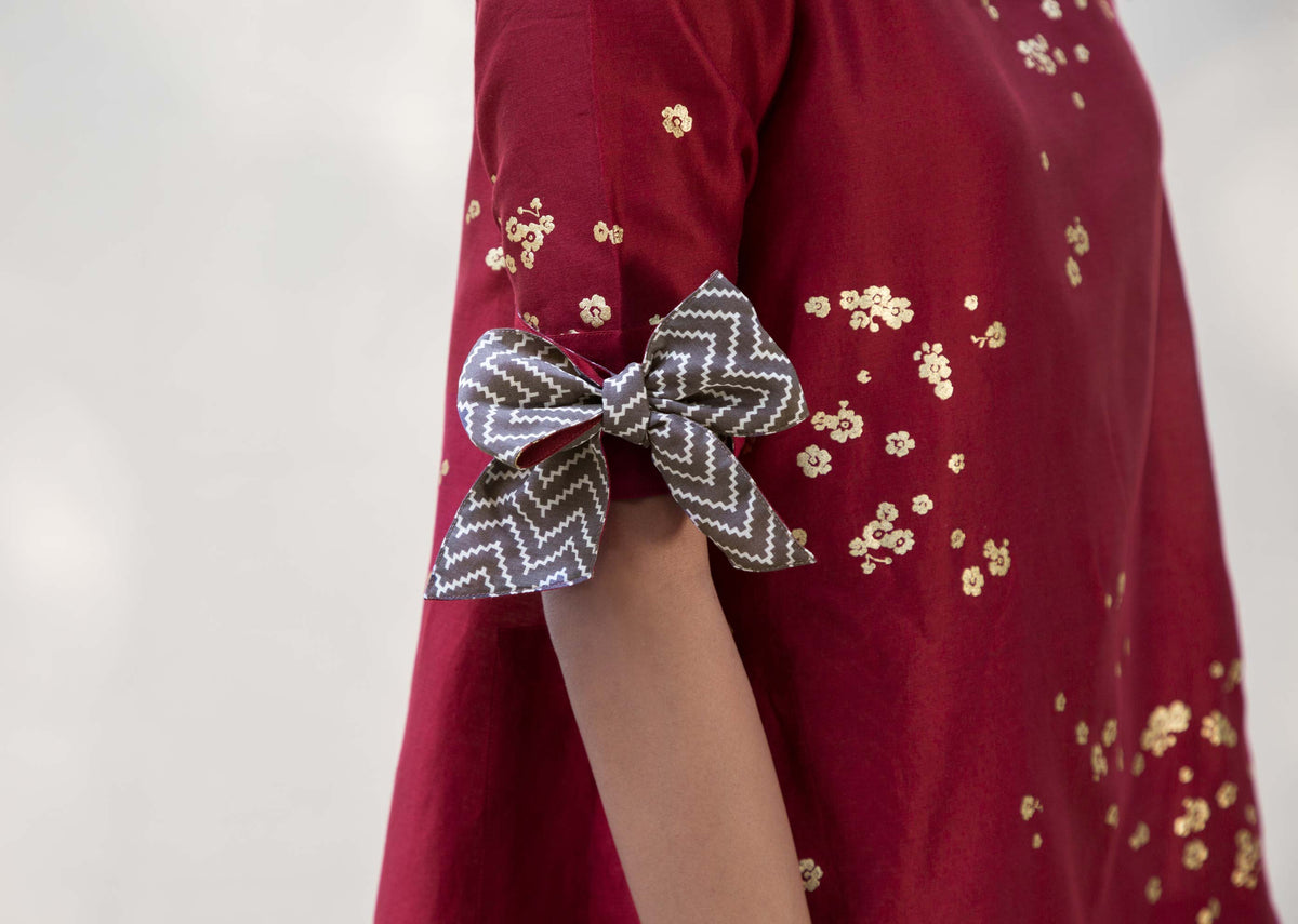 Close-up of a tie-up sleeve on a red Side High Slit Top with a chevron-print bow.