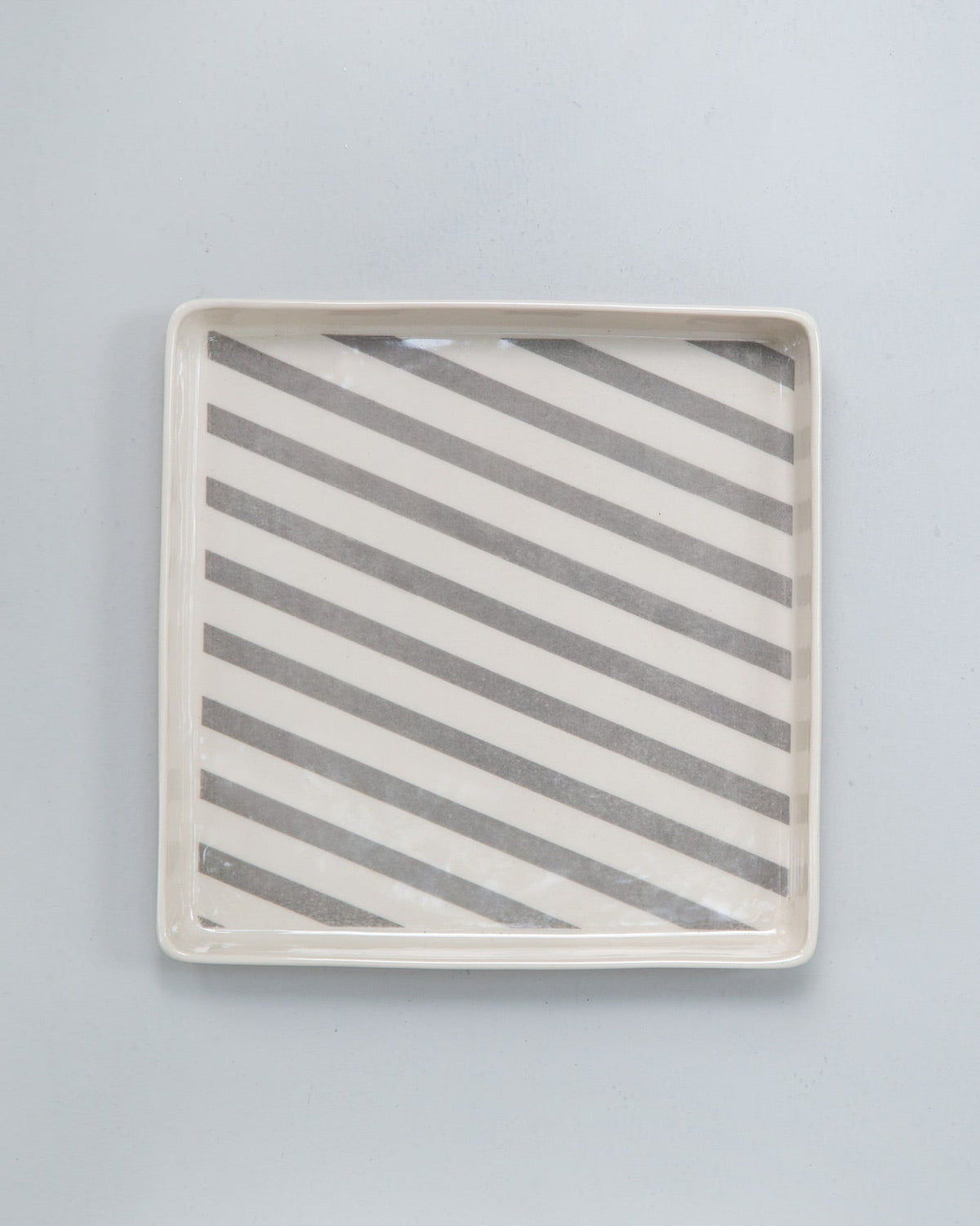 Close-up of a Colombo Cookie tray with Tongs showing its white and grey diagonal stripes.