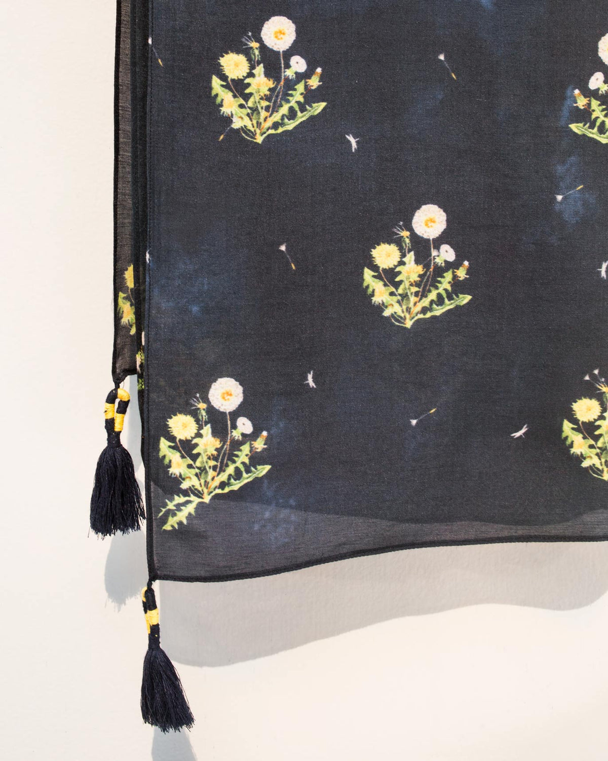 Close-up of Dandelion Scarf showing its yellow floral motifs and tassel ends.