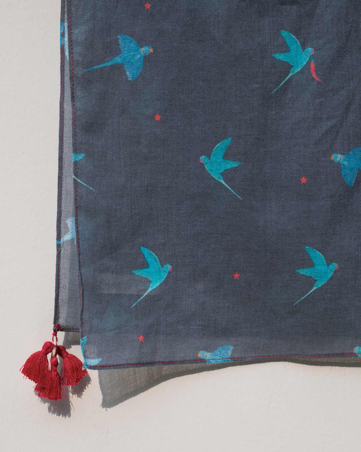 Close-up of the Neverland Scarf corner showing its bird print and red tassels.