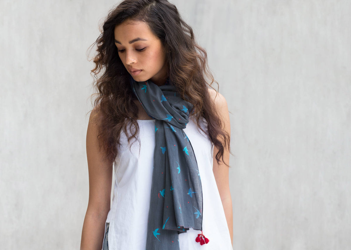 Person wearing a Neverland Scarf in blue-grey with a turquoise bird print.