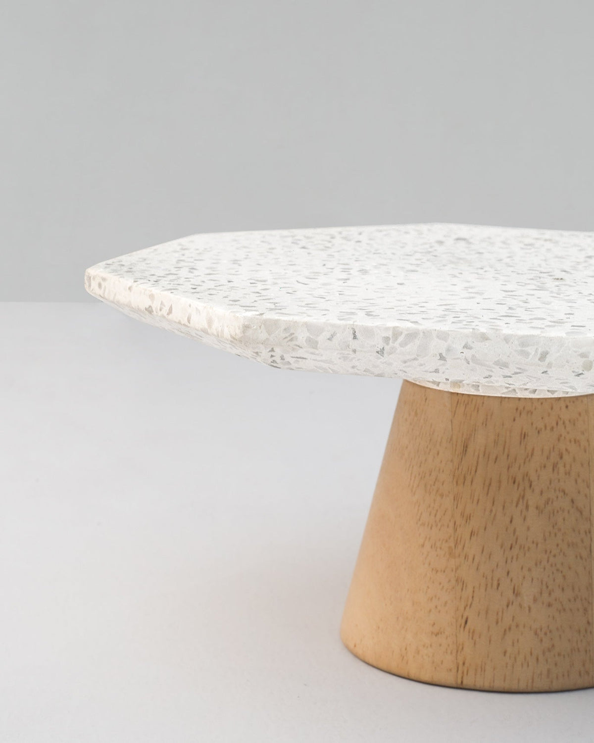 Close-up of a Colombo Cake Stand - Small showing its speckled edge and wooden base.