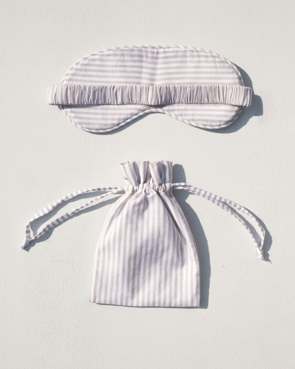 Star Snooze Eye Mask and drawstring pouch laid flat in grey stripes.