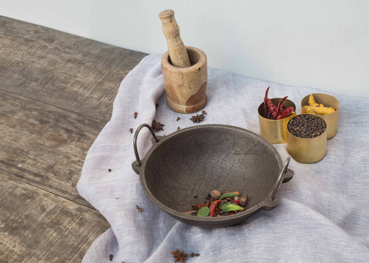 Cast Iron Kadai with spices in the pan, seen at an angle.