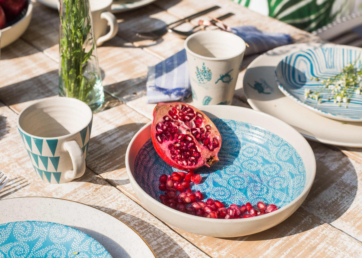 Dot Shallow Bowl holding pomegranate seeds on a set wooden table.