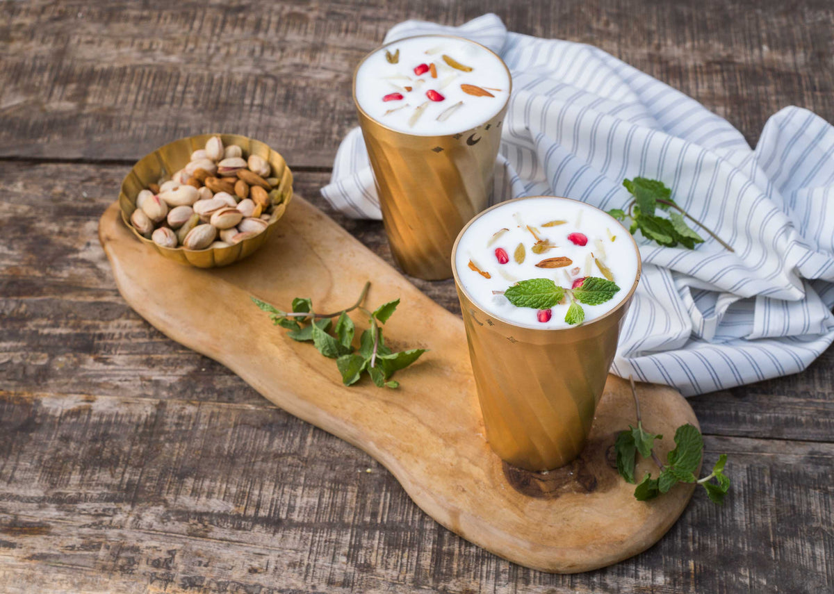 Two Diamantina Glasses in gold filled with a creamy drink.