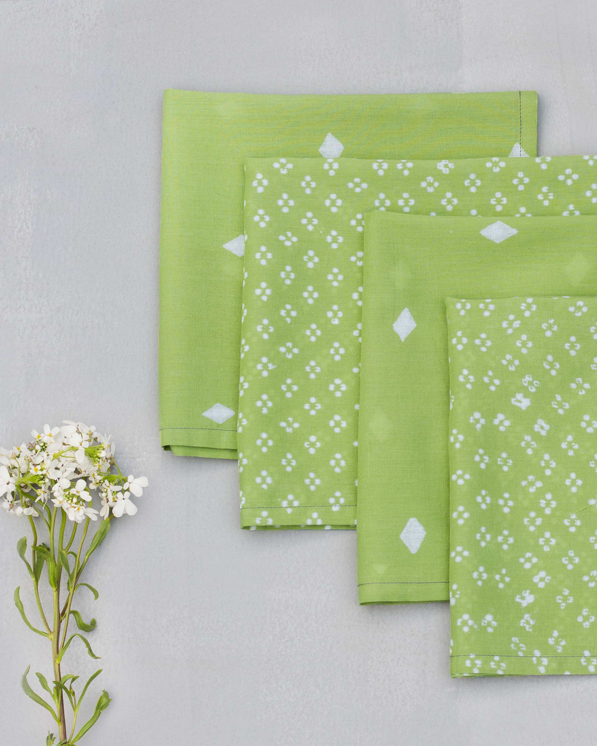 Overhead view of four green Diamond Dinner Napkins with white prints.