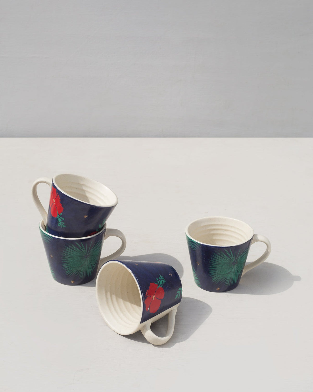 Wonderland Espresso Mugs turned at angles, showing their ridged white interiors.