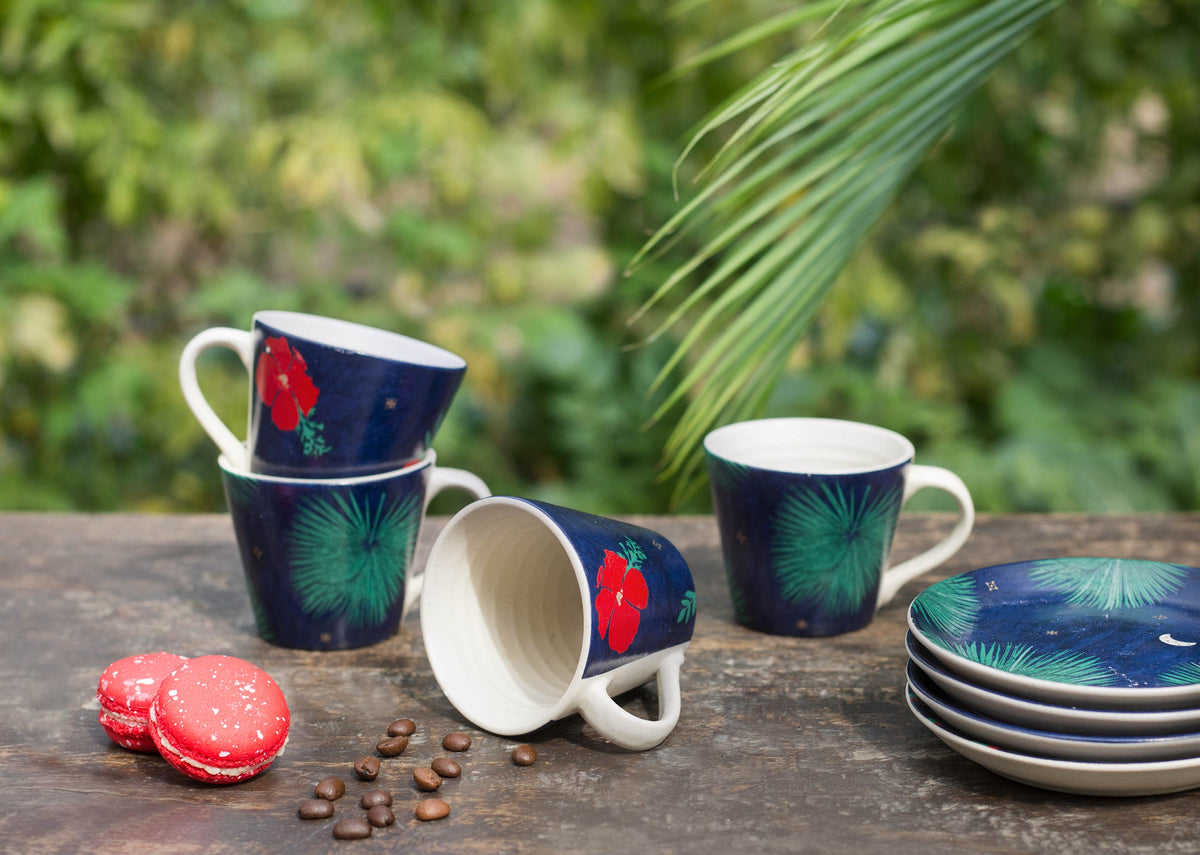 Wonderland Espresso Mugs in navy beside a stack of matching saucers.