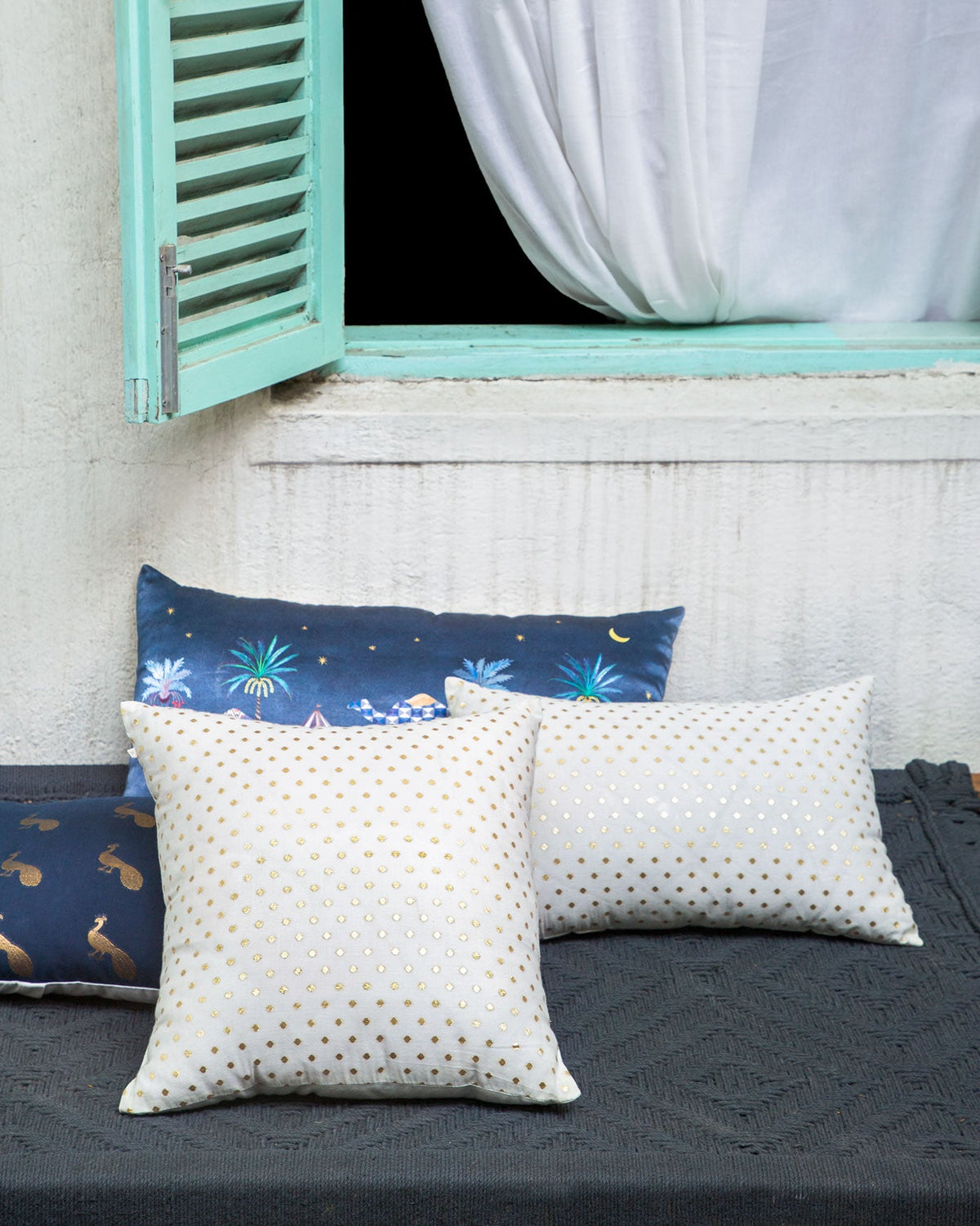 Dot Cushion Cover with gold dots, shown on a dark bench.