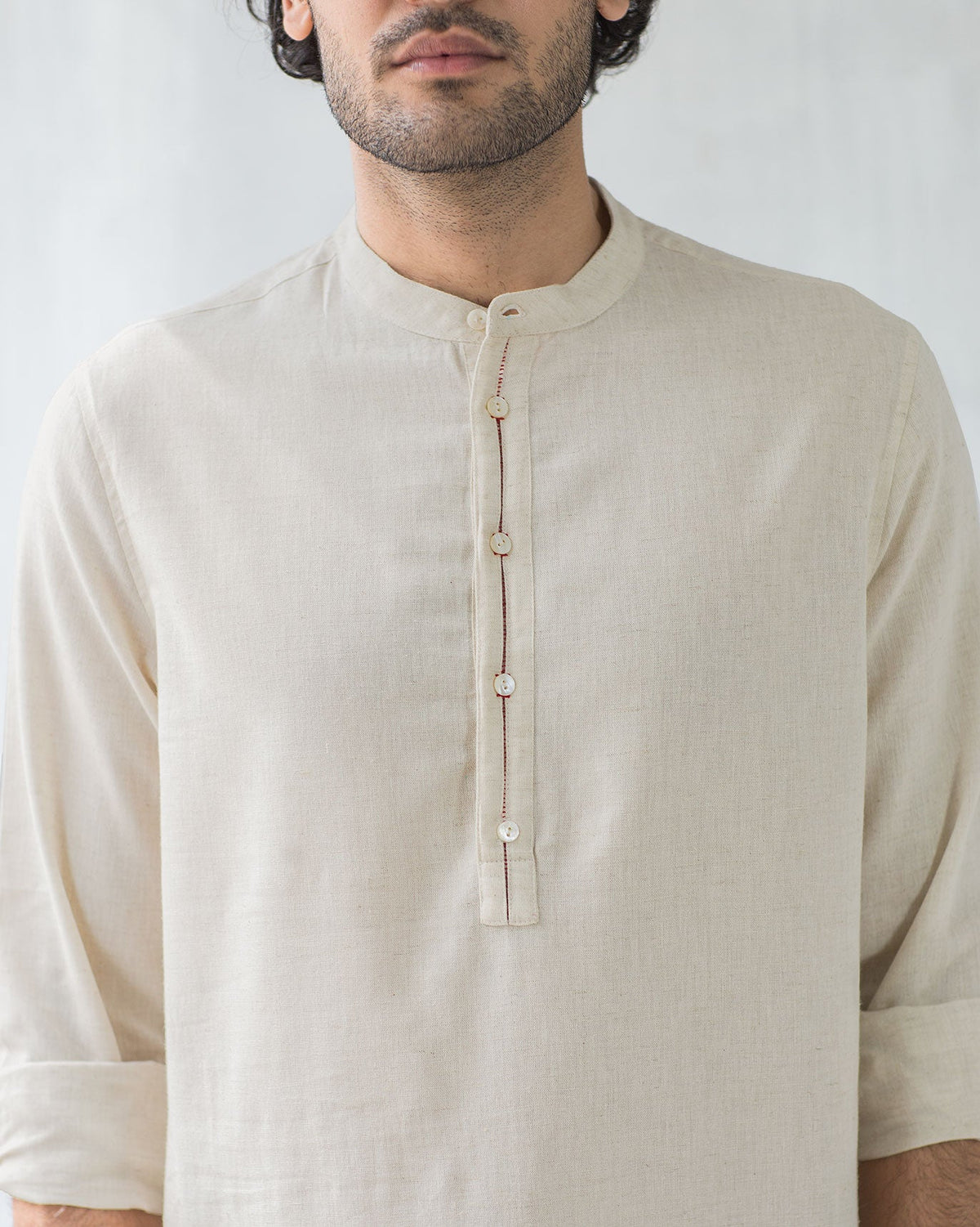 Close-up of a Chandni Chowk kurta showing the placket buttons and red thread detail.