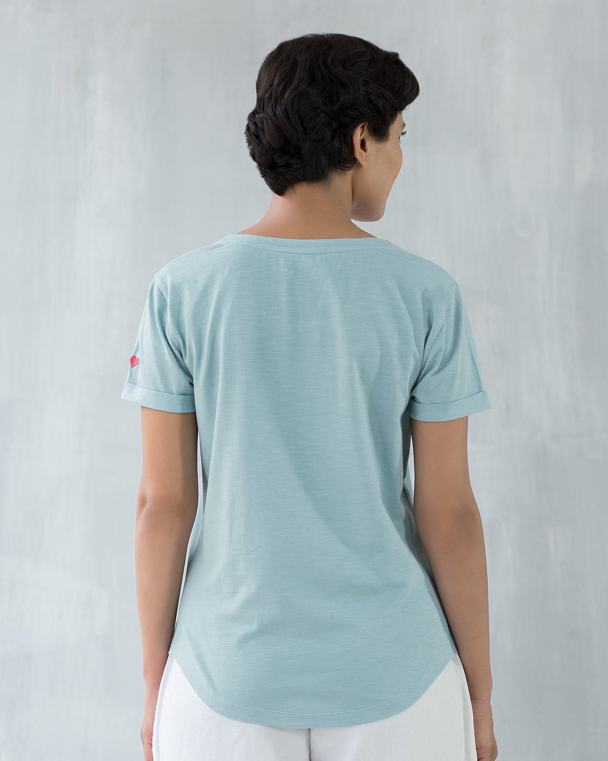 Back of a pale blue Basic T-shirt worn by a person.