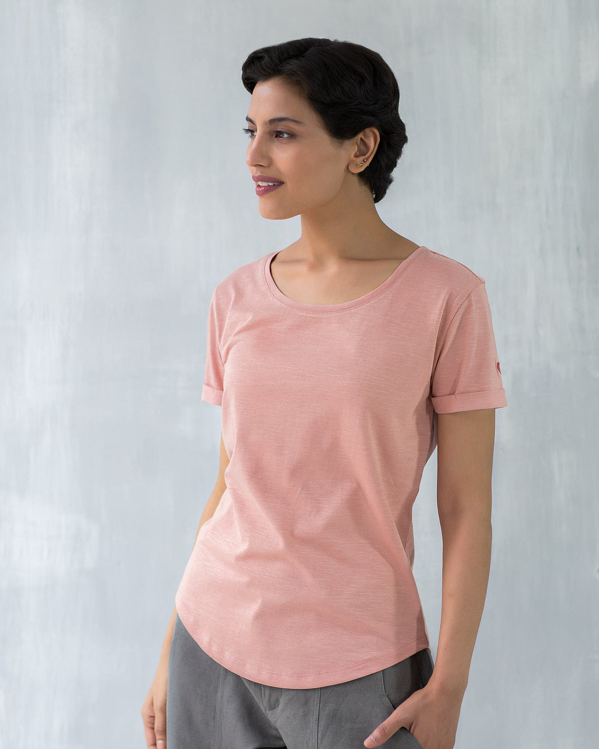 Person wearing a pink Basic T-shirt with rolled sleeves.