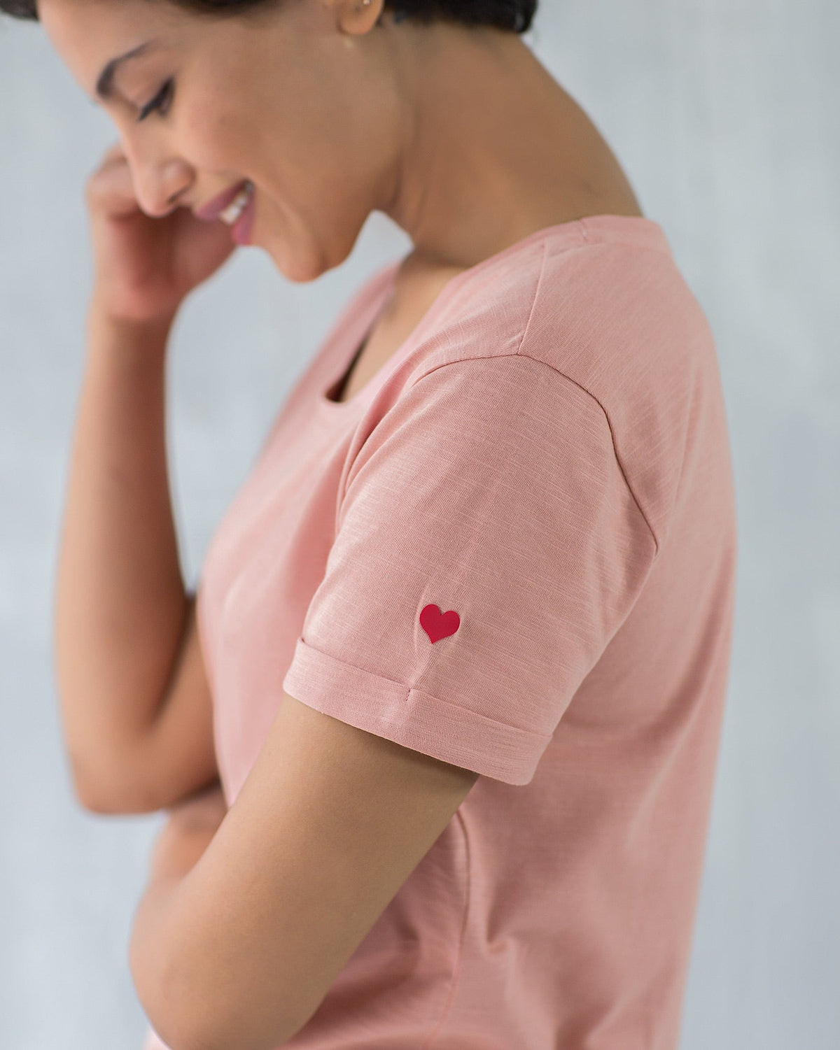 Close-up of a pink Basic T-shirt sleeve showing a red heart embroidery.