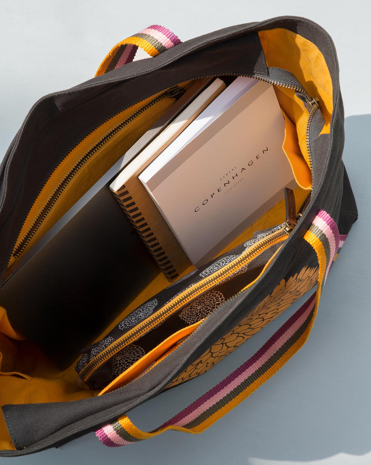 Open Marigold Tote with a book and a dark case inside.