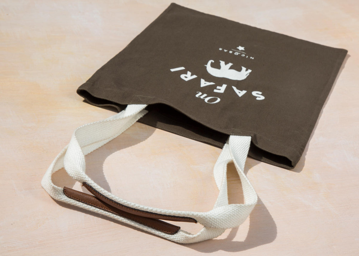 On Safari tote lying at an angle, showing its cream handles and leather grip.