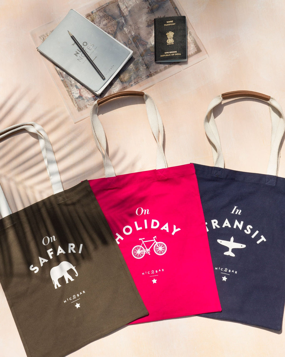 Pink On Holiday tote shown alongside olive and navy canvas totes.