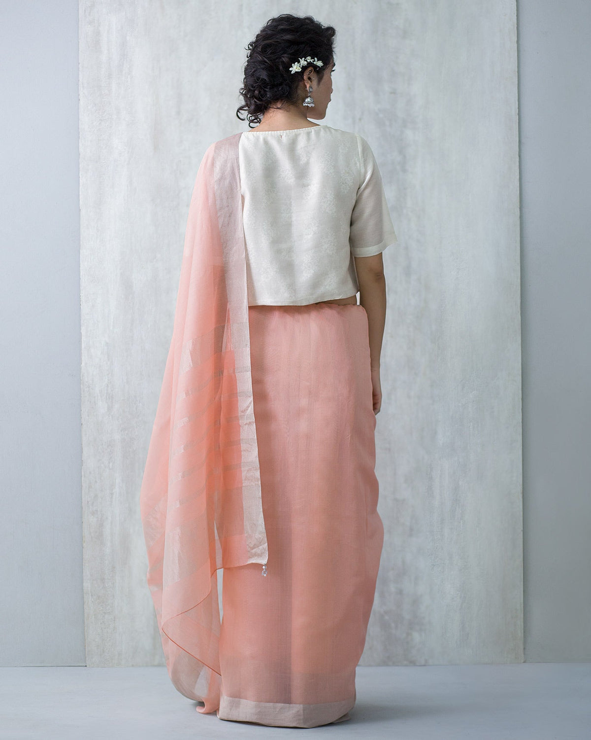 Back of a pink Serai Sari with a cream blouse worn by a person.