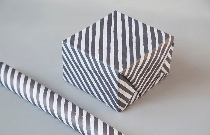 Wrapping sheet in grey and white stripes wrapped around a box, with a roll beside it.