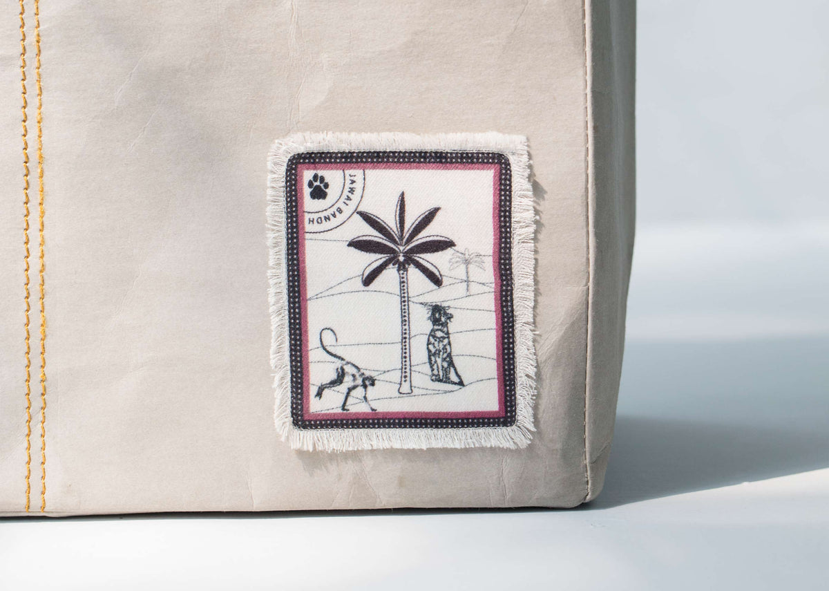 Close-up of Jawai Paper Tote showing its fringed patch with a palm tree.