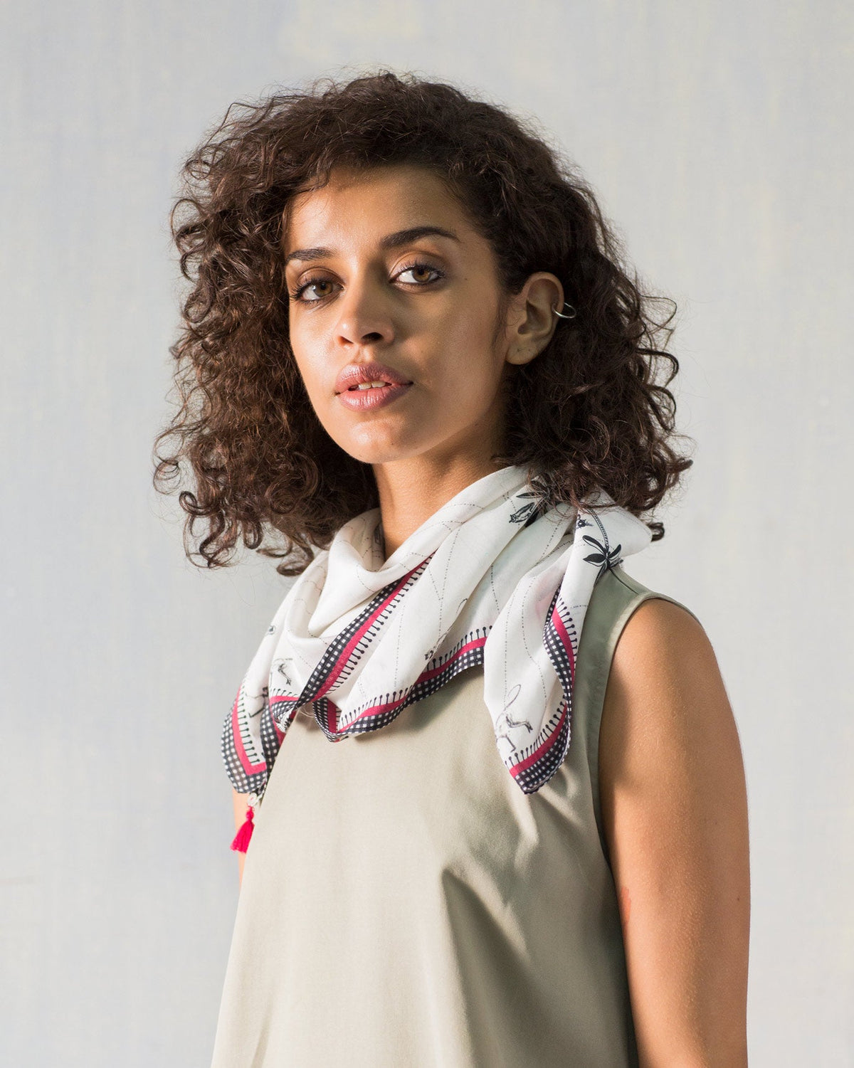 Person wearing a white Jawai scarf with a black and pink gingham border.