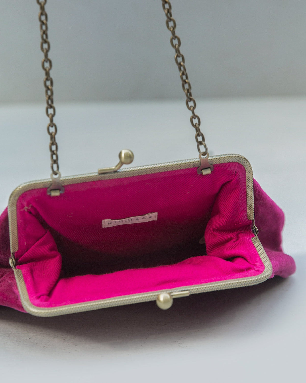 Romani Clutch open at the frame clasp, showing its magenta lining.