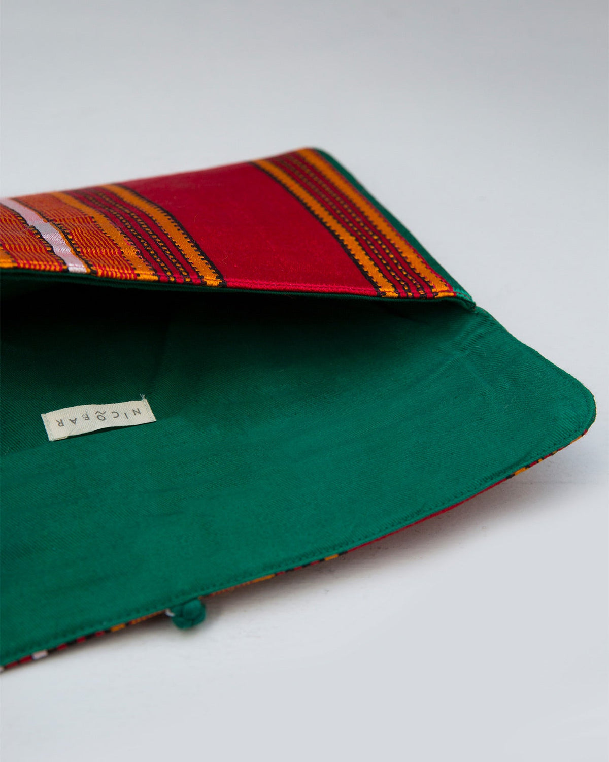 Open Stripe Flap Clutch showing its green lining and a brand label.