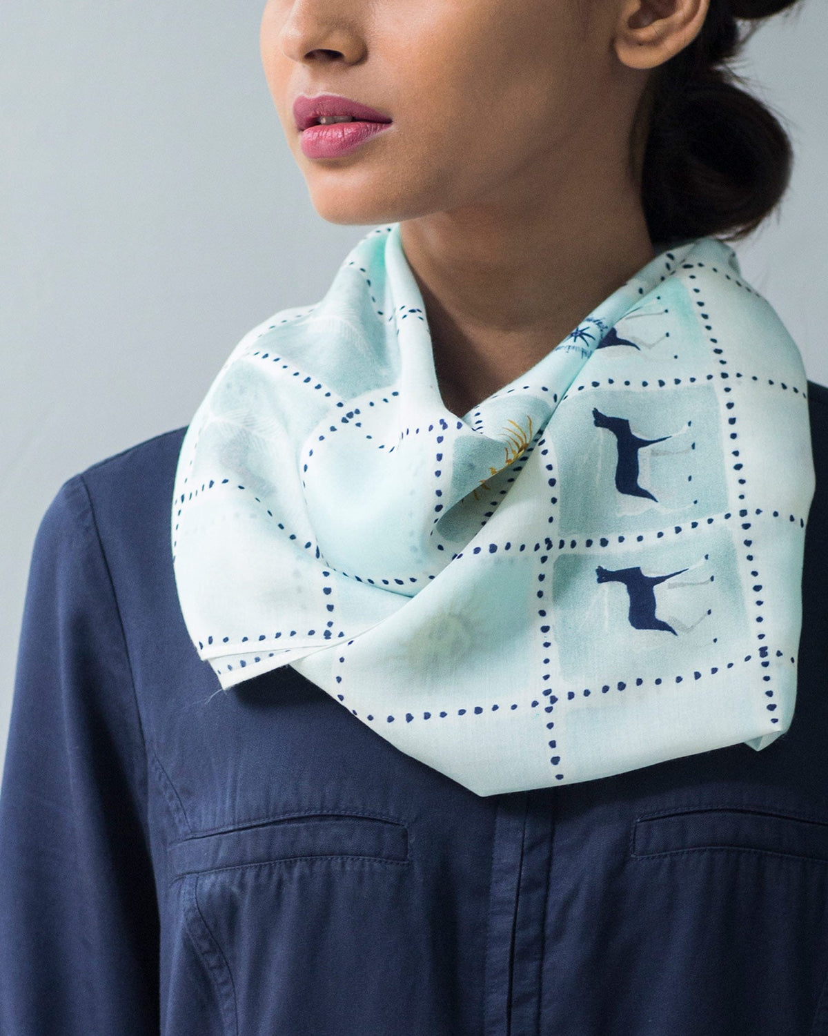 Person wearing a Stamp Scarf draped loosely around the neck.