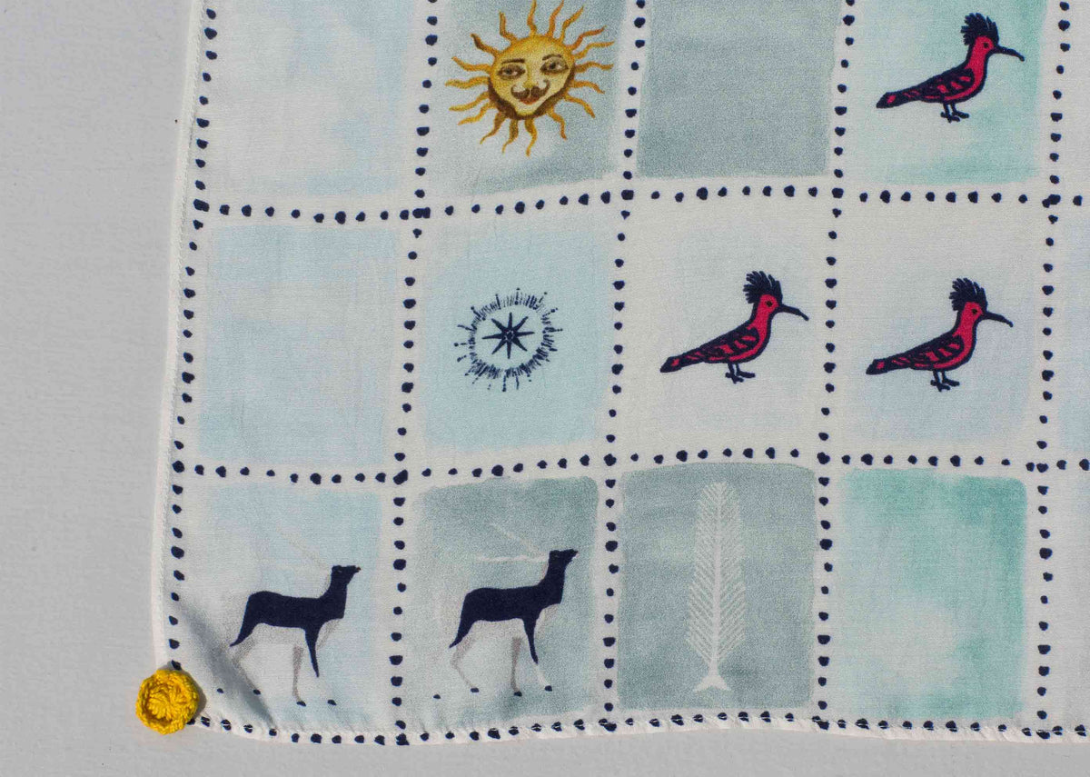 Close-up of Stamp Scarf showing a sun, compass star and red birds.