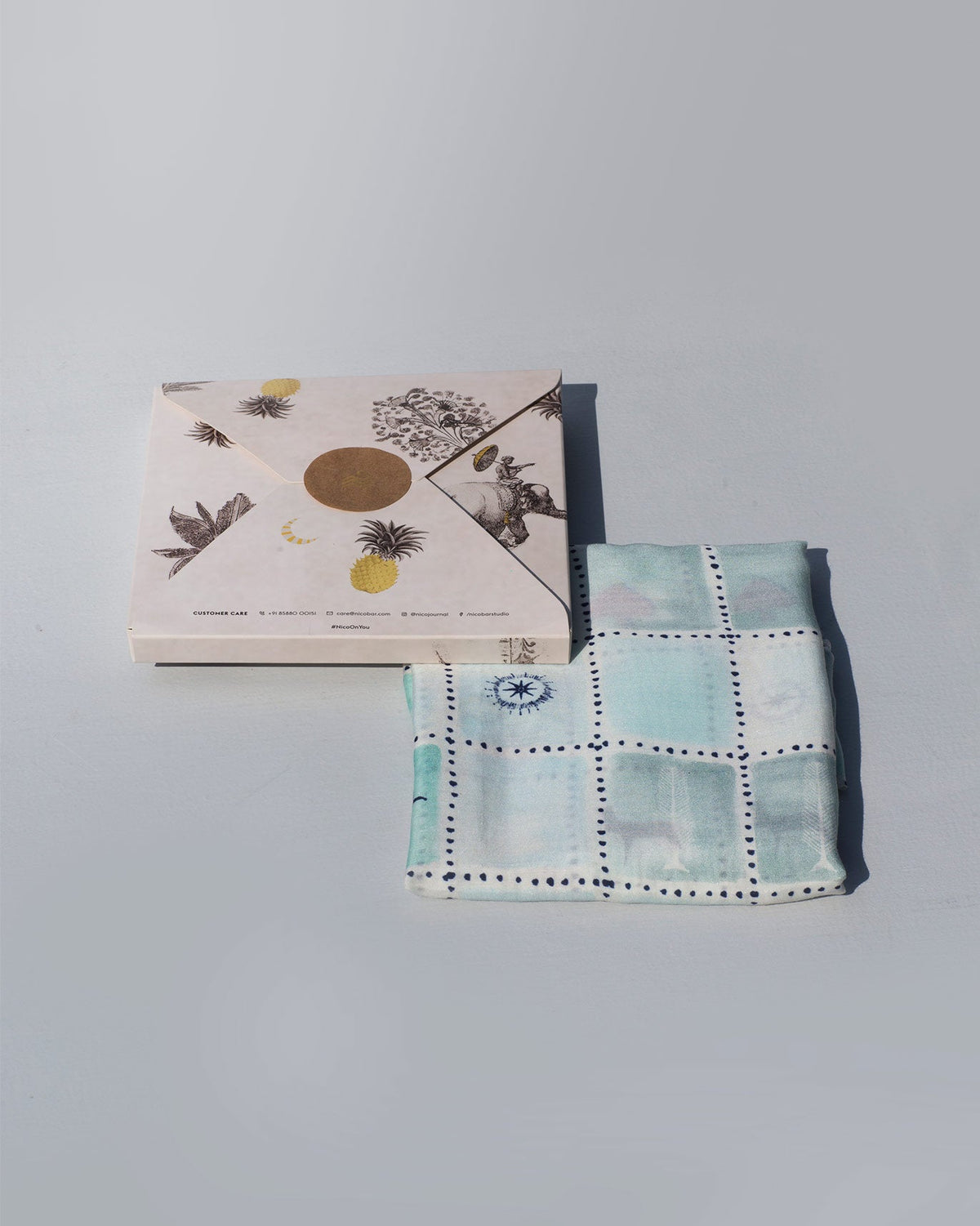 Stamp Scarf folded beside its printed gift box.