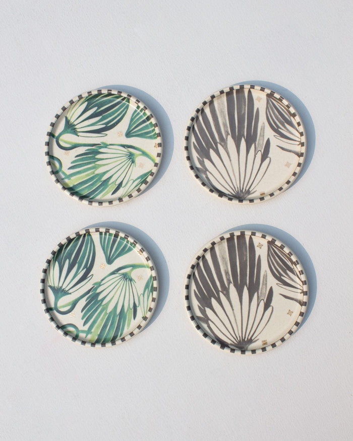 Set of four Palm Coasters with green and grey leaf designs laid flat.