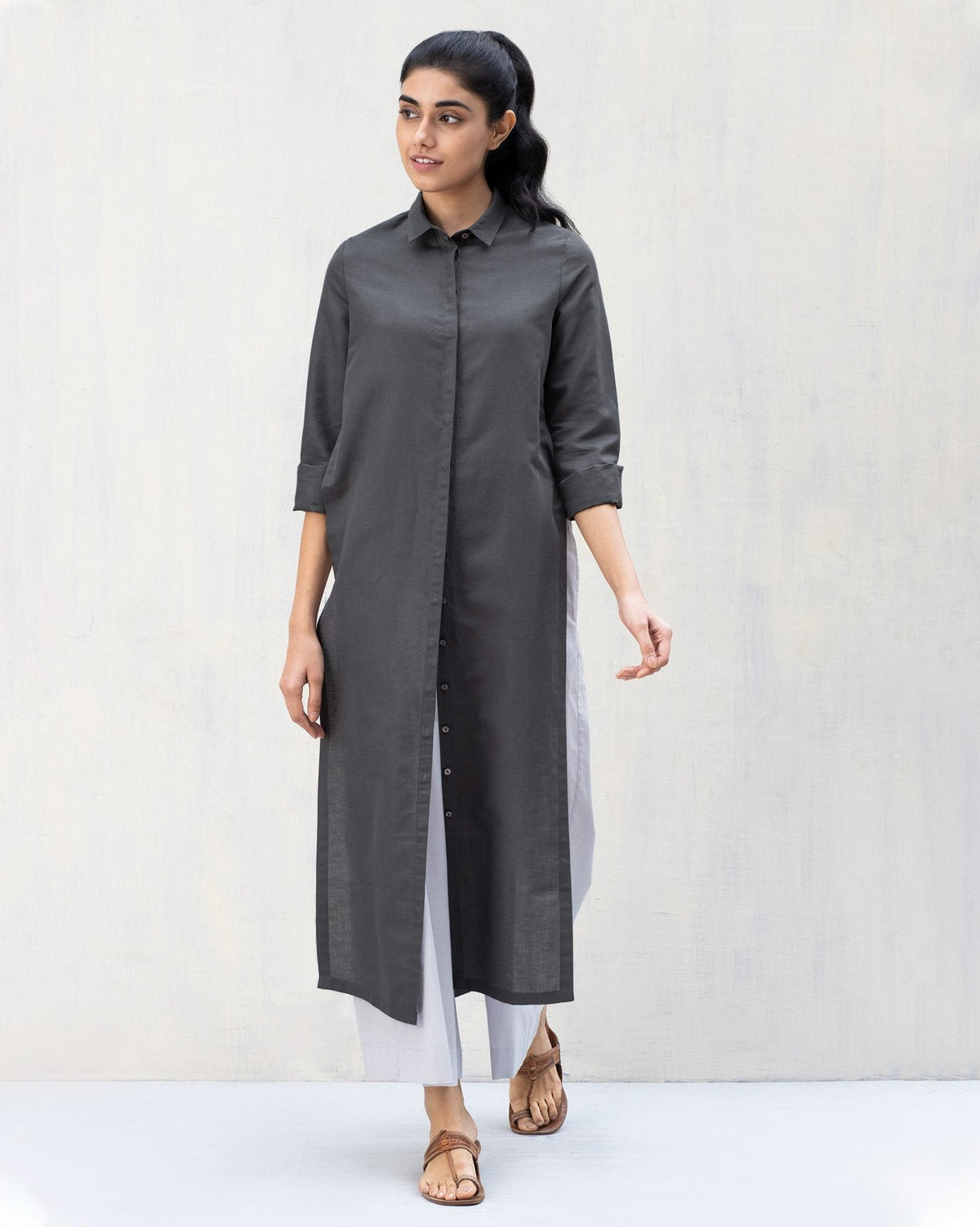 Person wearing a long charcoal Many Moons Kurta with a collared neck and side slits.