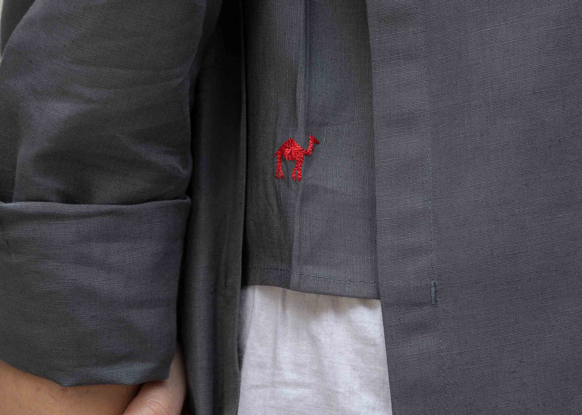 Close-up of a small red embroidery on the side panel of a charcoal Many Moons Kurta.